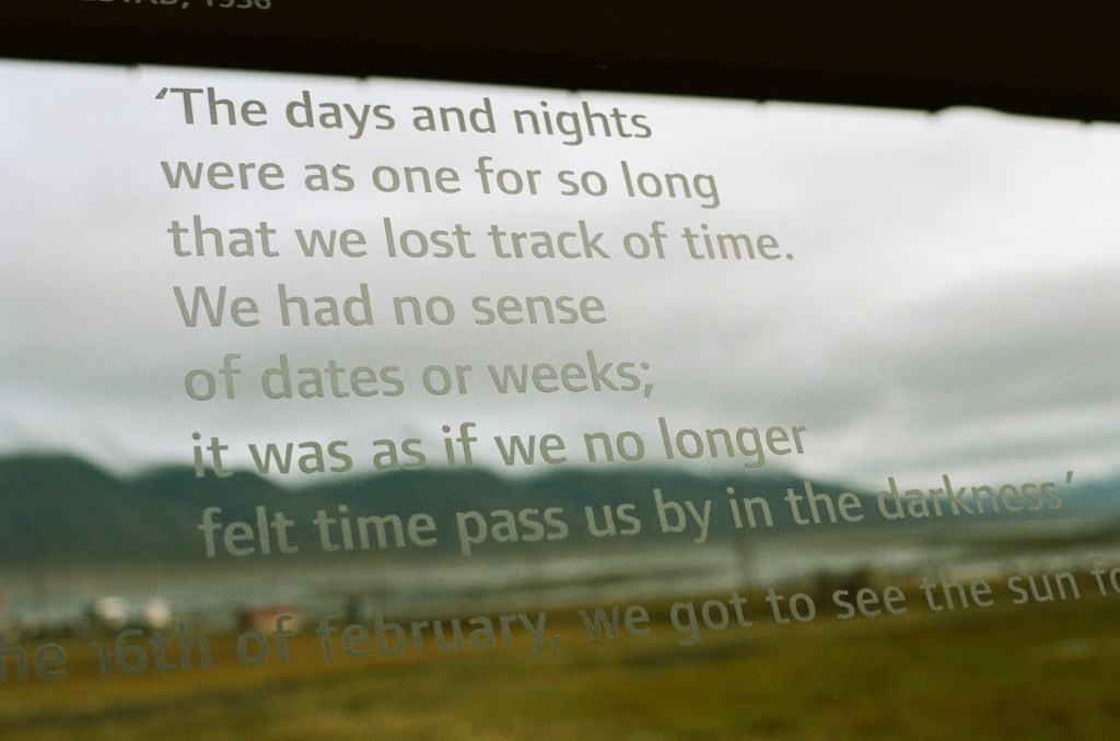 'The days and nights were as one for so long that we lost track of time. We had no sense of dates or weeks; it was as if we no longer felt time pass us by in the darkness' is printed on the window, a scenic image is blurred in the background. 