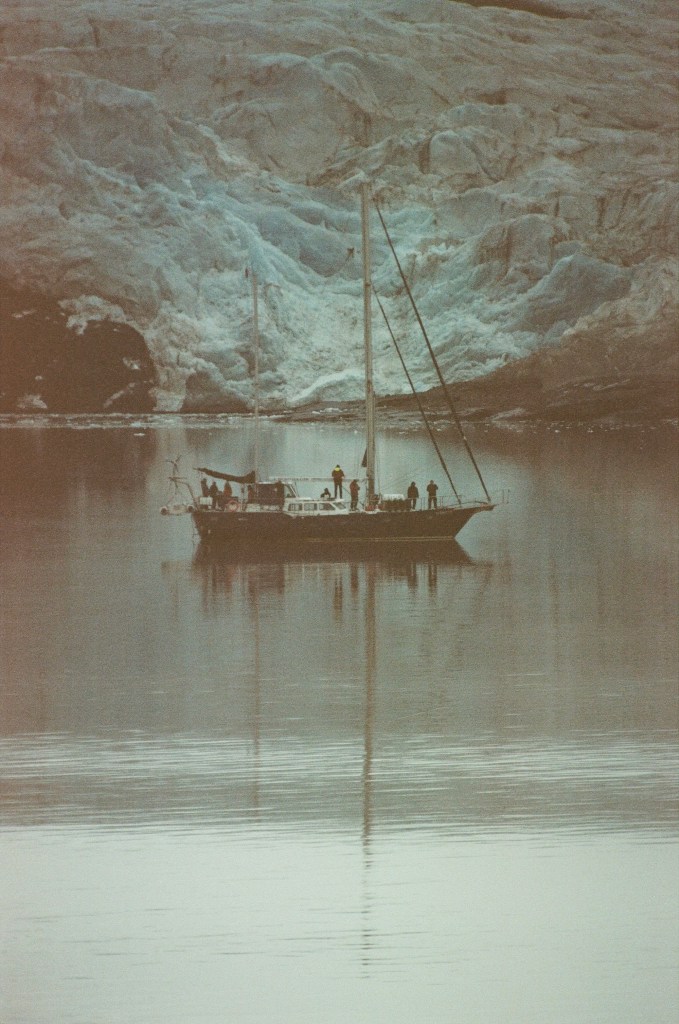 Sail boat and reflection in front of a glacier. 
