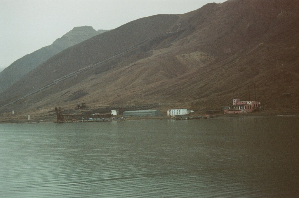 An industrialised shore line can be seen on the side of the base of a mountain. 