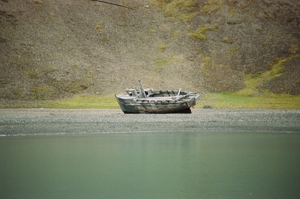 The scene shows a shore with a wooden boat lent up on the side. 