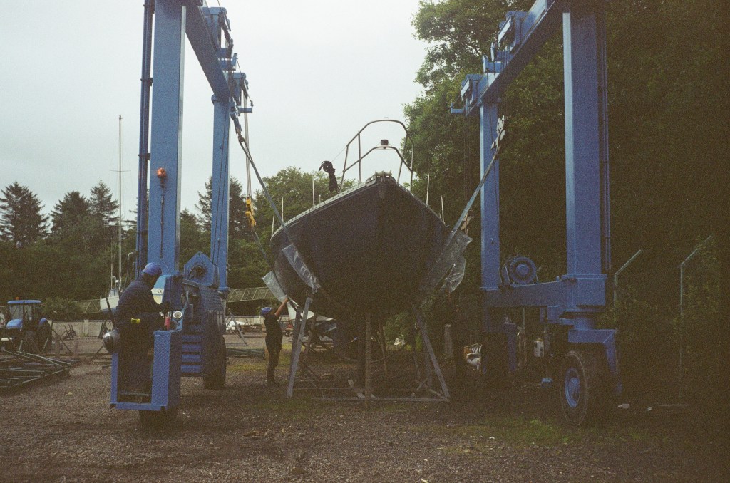 A boat with slings under it ready to be lifted can be seen from the front,  it is currently still in its cradle. 