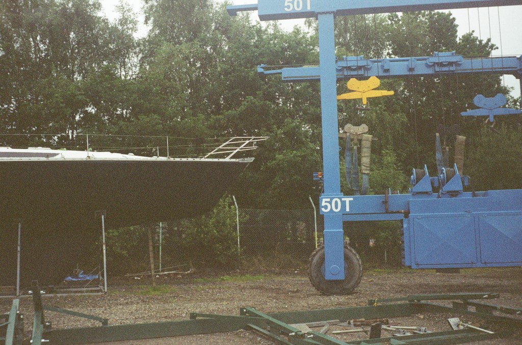 A large blue winch vehicle can be seen approaching the front of a large boat in its cradle. 