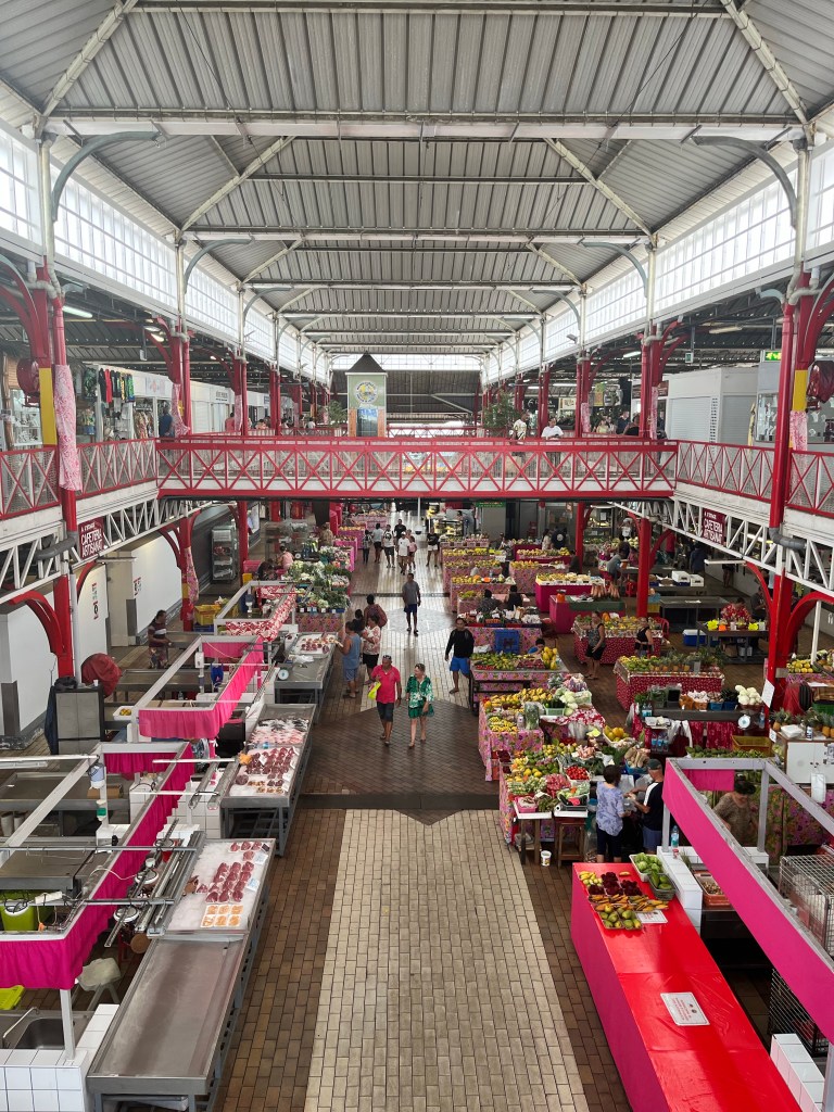 A two level building filled with market stands and people walking through the middle. 