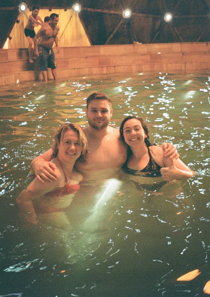 A man stands between two women in a pool.