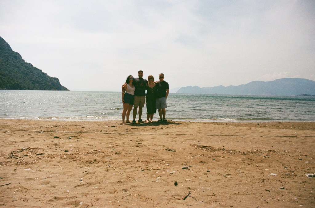 2 men and 2 women stand together on a beach.