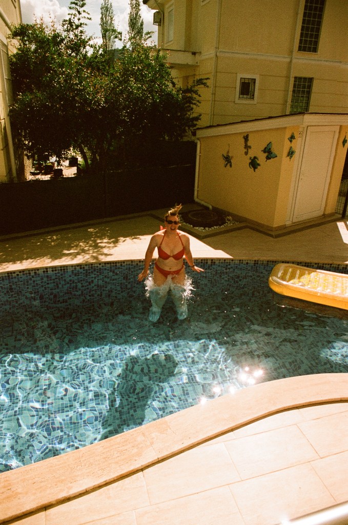 A woman in a red bikini jumps into a swimming pool.