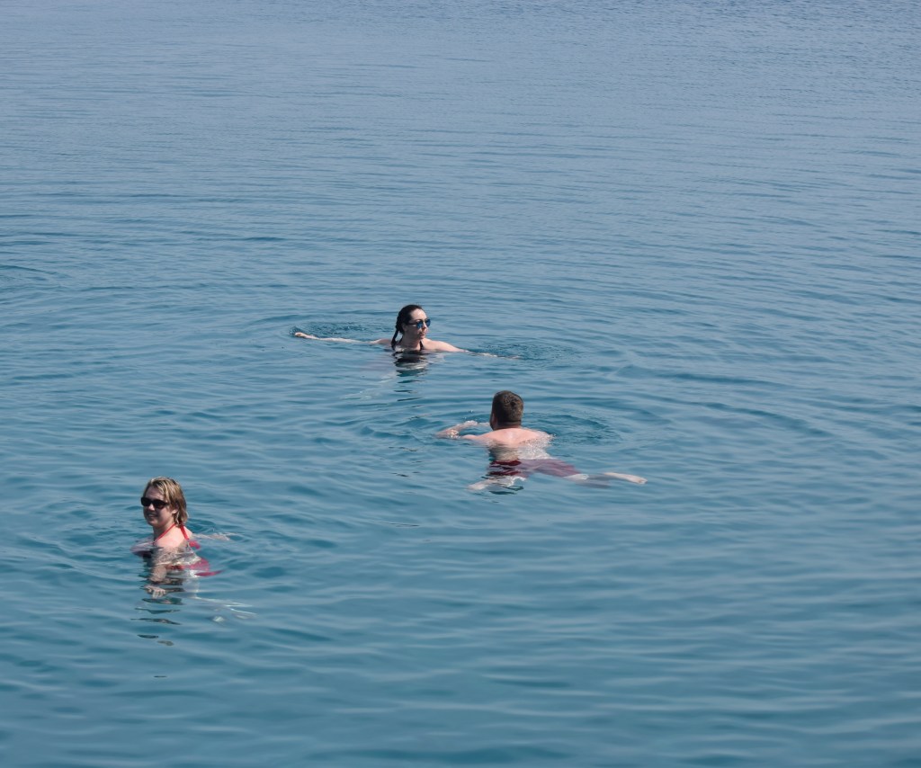 A man and two women are swimming in water.