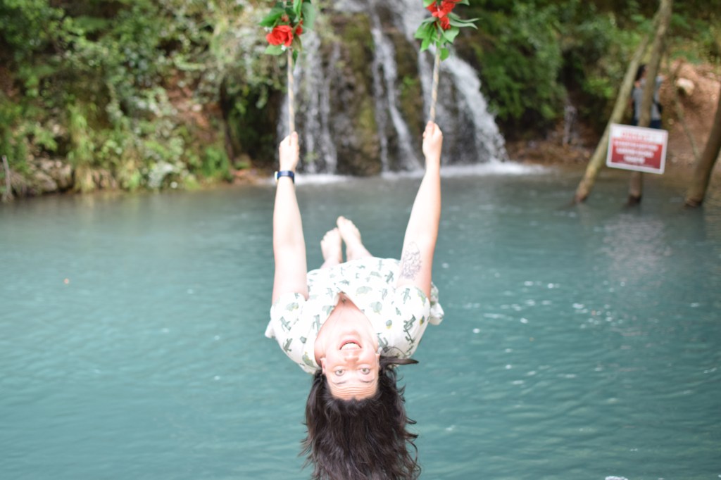 A brunette woman is pictured swinging away but leaning back to look at the camera.